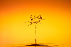 An image of a water drop hitting the water in front of a yellow background